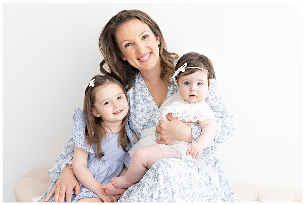 mom wearing beautiful blue dress with daughters for a baby photography session 