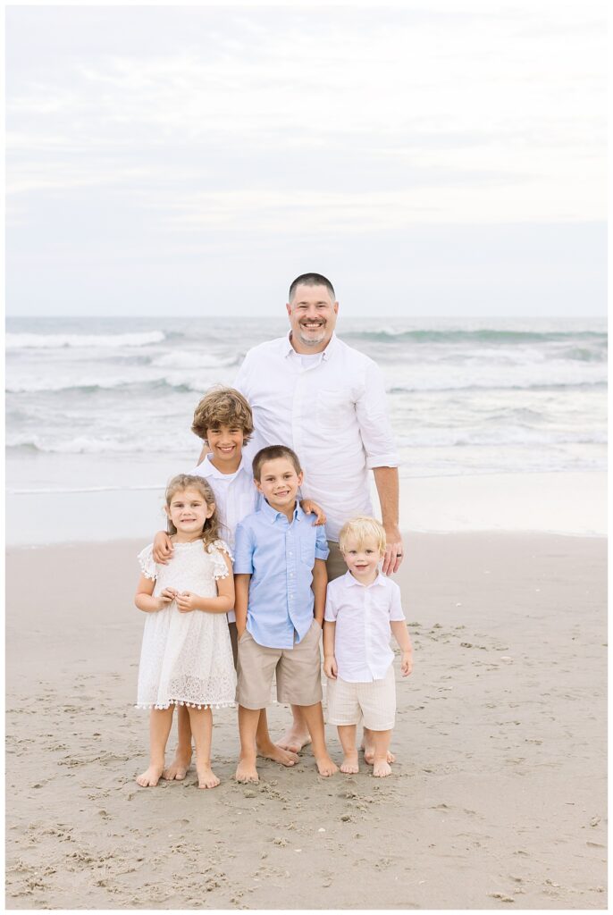 dad standing on the beach for a portrait with his four kids