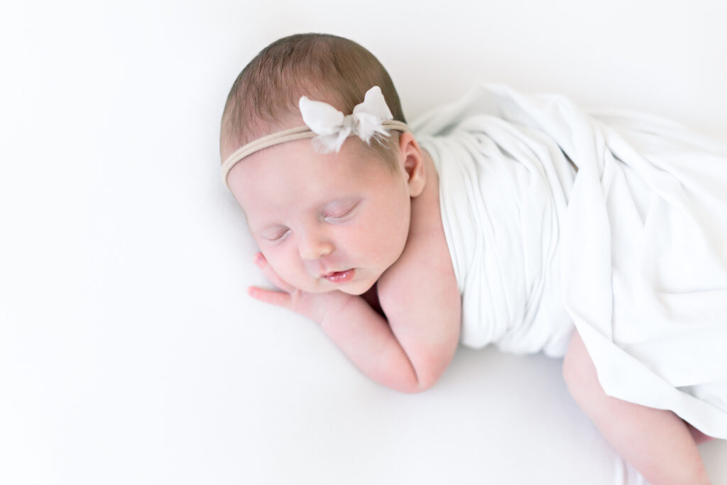 baby girl laying on hand newborn photos
