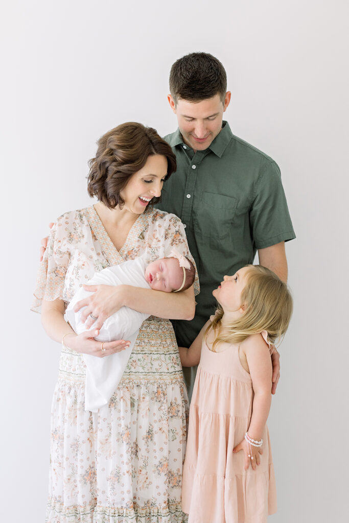 family of four looking and smiling at baby