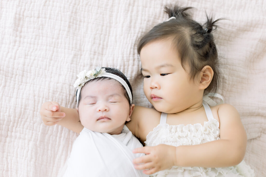 sibling photographer sister looking at baby newborn sibling photoshoot
