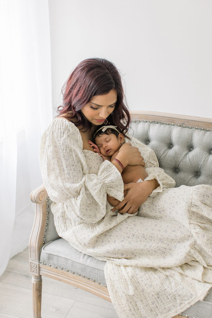 mom snuggling baby girl on sofa newborn photography philadelphia