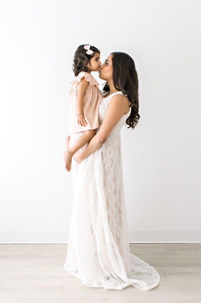pregnant mom kissing daughter maternity pictures