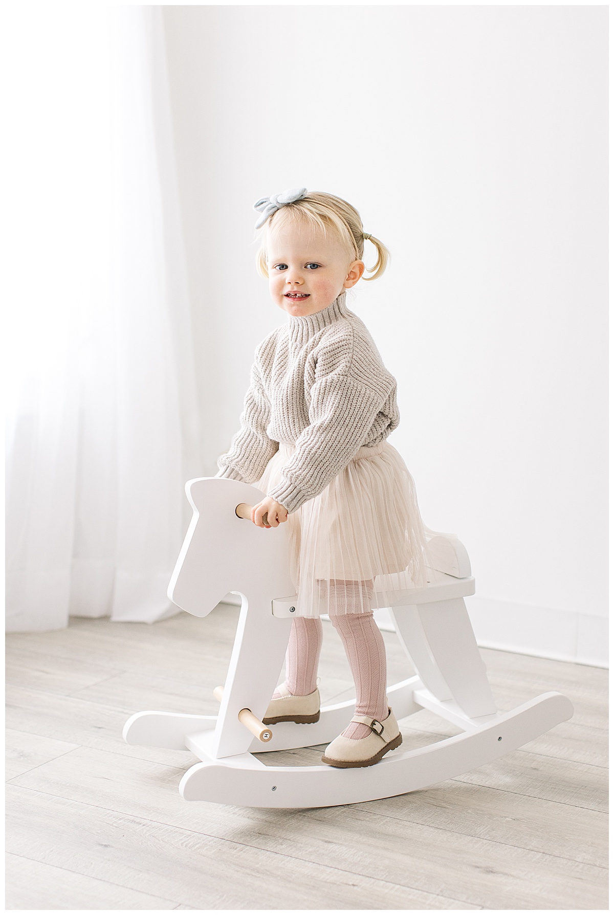 little girl looking at camera rocking horse pictures studio