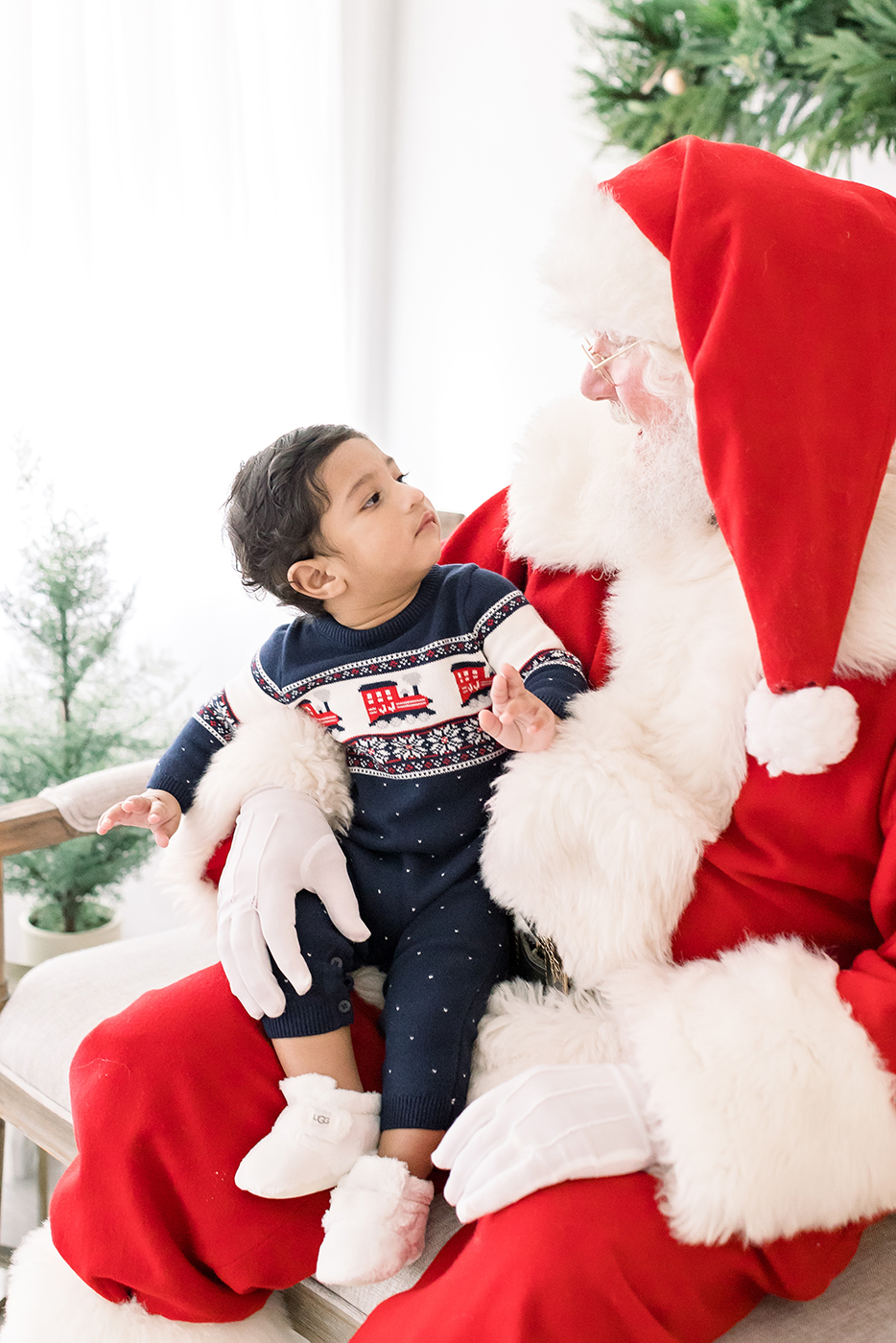 little boy in blue outfit looking at santa 