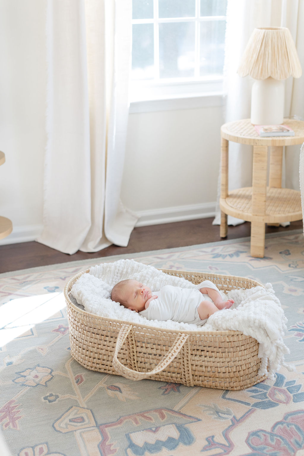 A newborn baby sleeps in a woven basket on the floor of a nursery under a window for a Philadelphia lifestyle newborn photographer