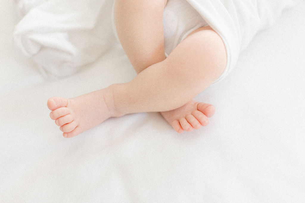 Details of a newborn baby's feet on a white bed