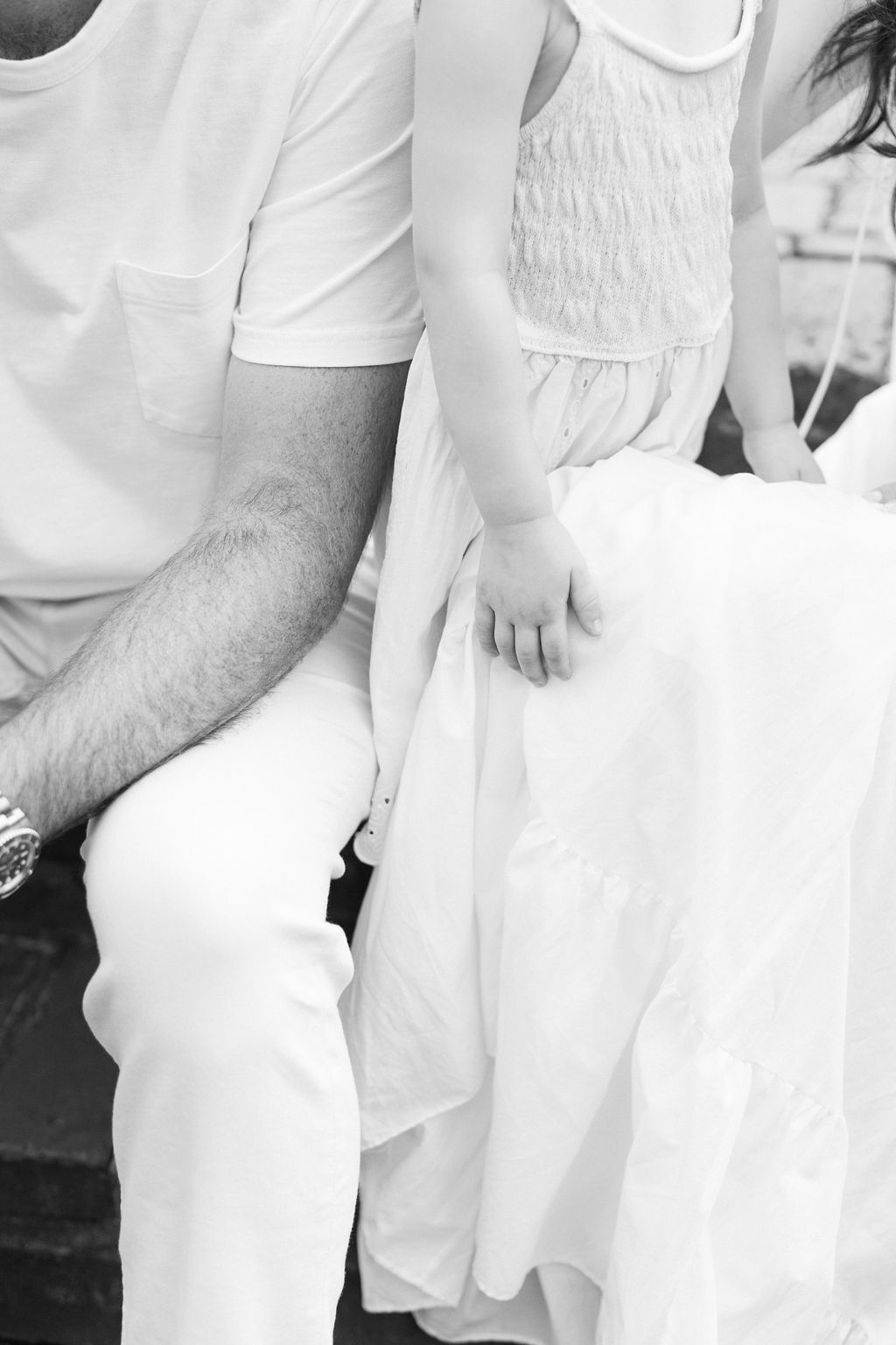 Details of a toddler girl standing on a bench between mom and dad