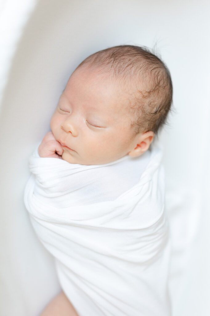 baby wrapped in white swaddle sleeping