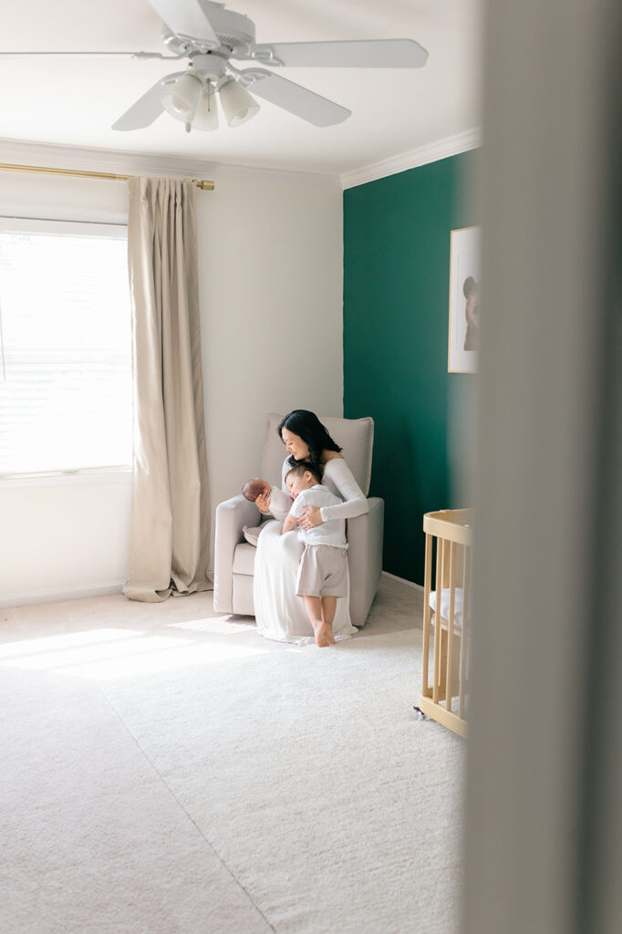 mom looking at newborn in green nursery