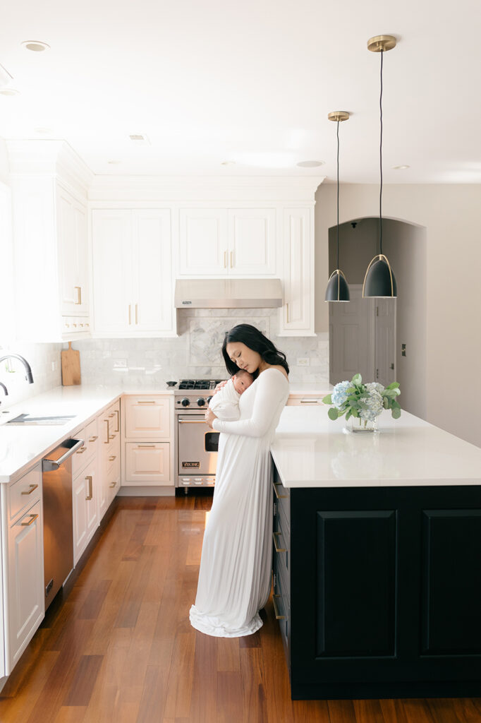 mom holding newborn white dress kitchen