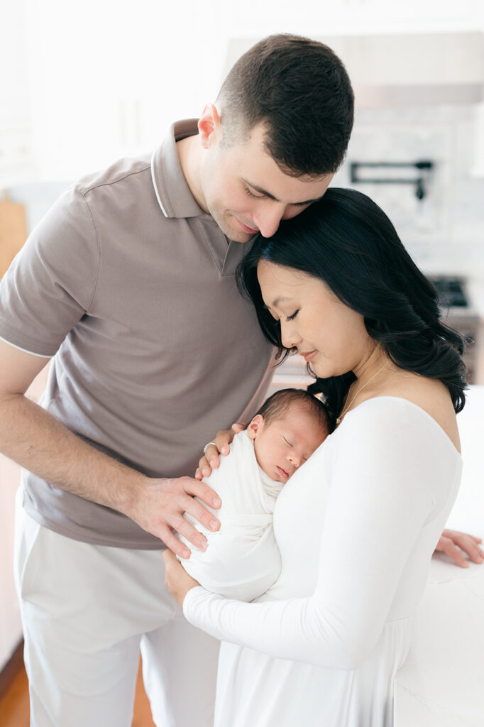 mom and dad with newborn baby swaddled