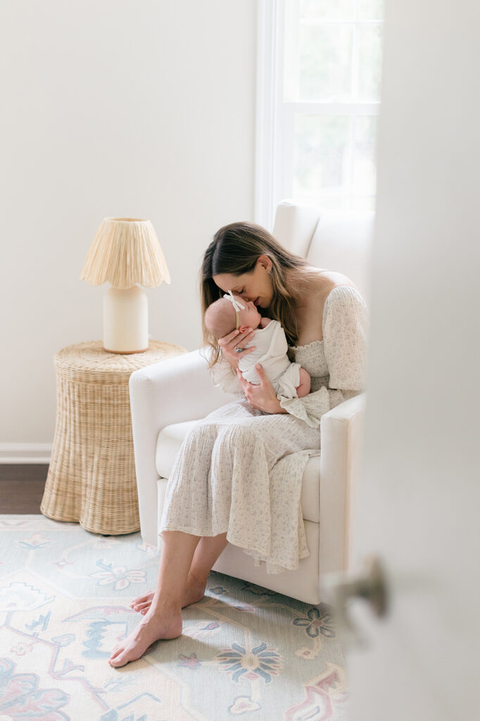mom snuggling newborn baby girl nursery
