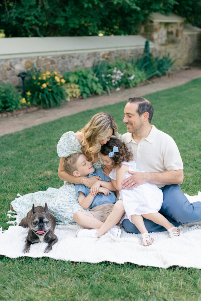 spring photos family snuggling on blanket on grass with dog