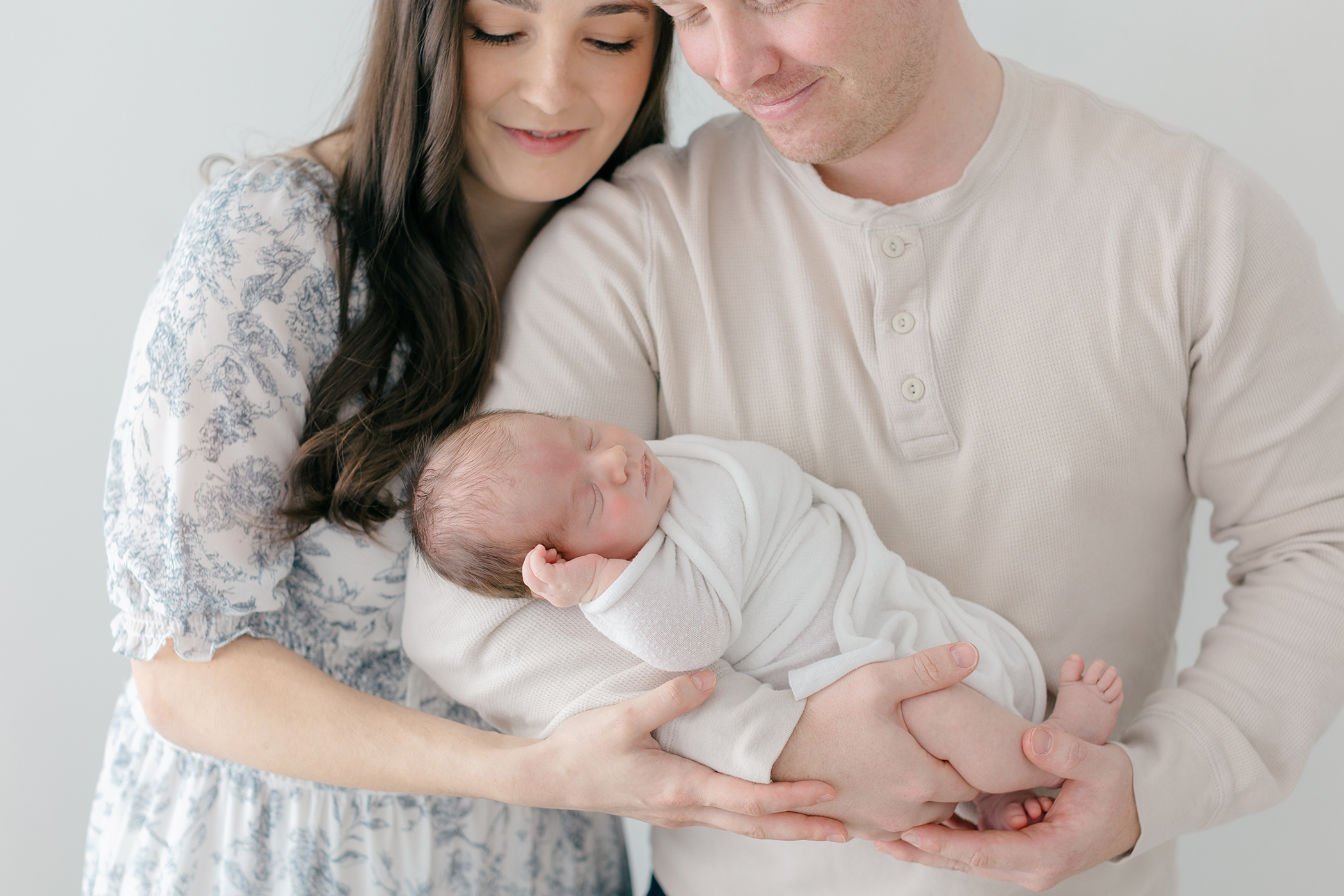 parents cuddling newborn baby during lifestyle photography session