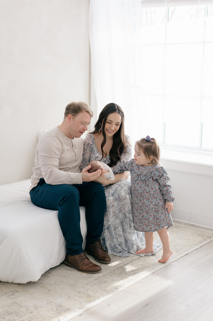 Family cuddling newborn baby during lifestyle photography session
